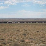 Long train with tanks on it next to Route 66